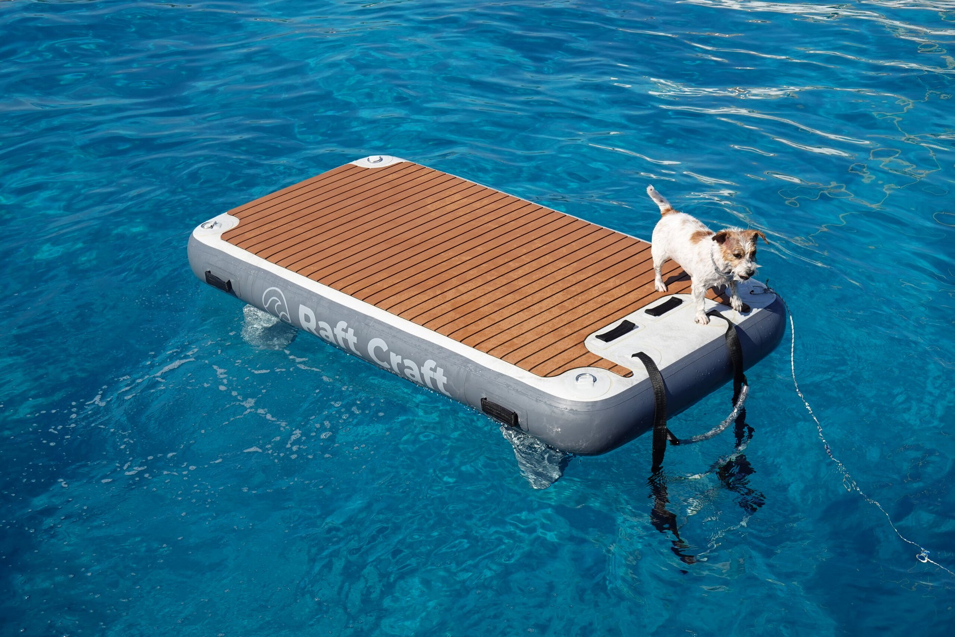 Raft Craft RC101 floating dock on open water, teak-effect deck and Raft Craft wordmark on the side tube