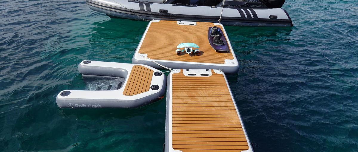 The Raft Craft range rafted up on clear teal water: the large floating dock carrying a sea scooter and a wakeboard, the small dock alongside it, and the large dog ramp with its sling visible below the surface